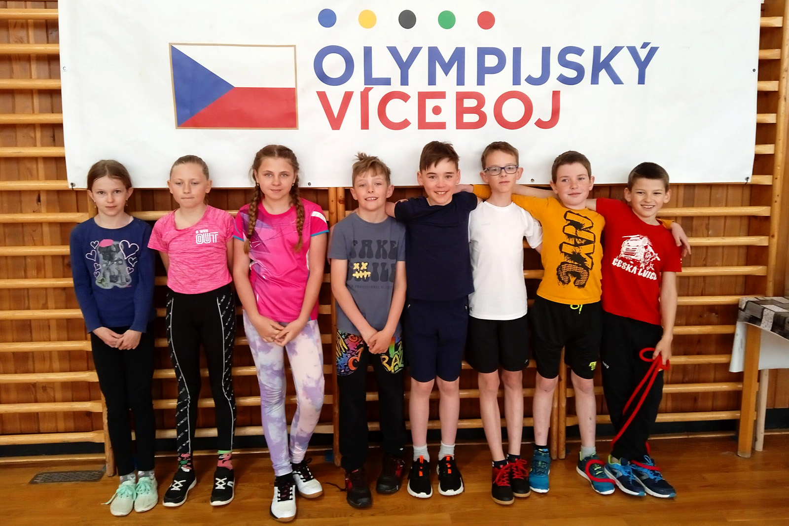 akce-Olympijsky-odznak-2024-01 Fotografie dětí stojících před bannerem olympijský víceboj